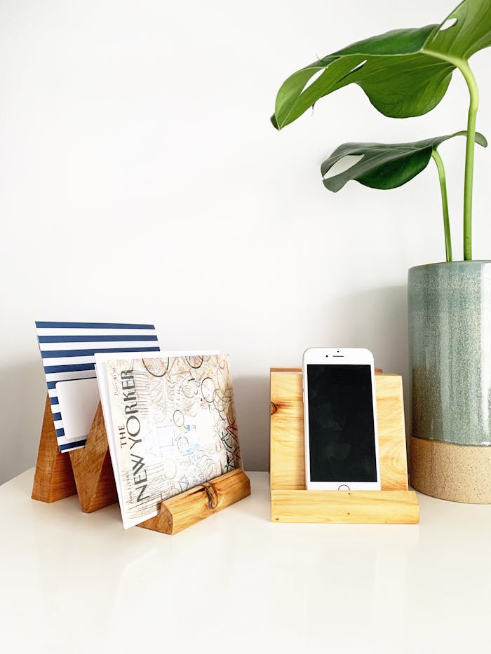 A clean desk with a plant, phone holder, and wooden magazine holders, perfect for a modern minimalist look.